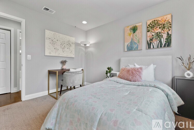 A bedroom with a bed, a chair, and a table with a plant on it.