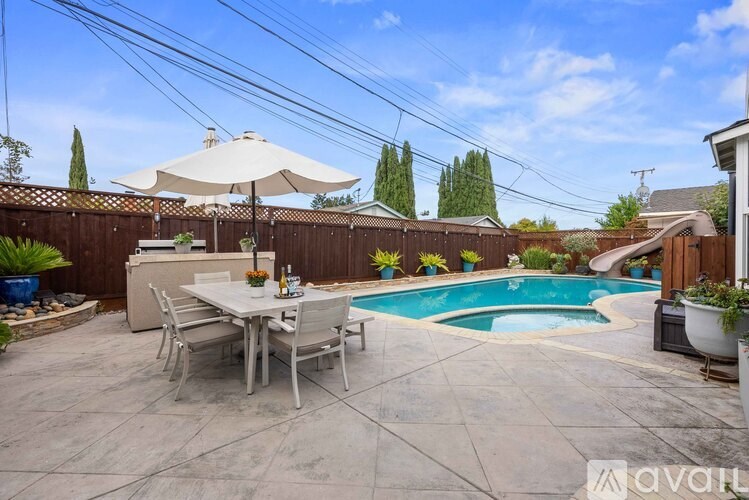 A patio with a table and chairs and a pool.