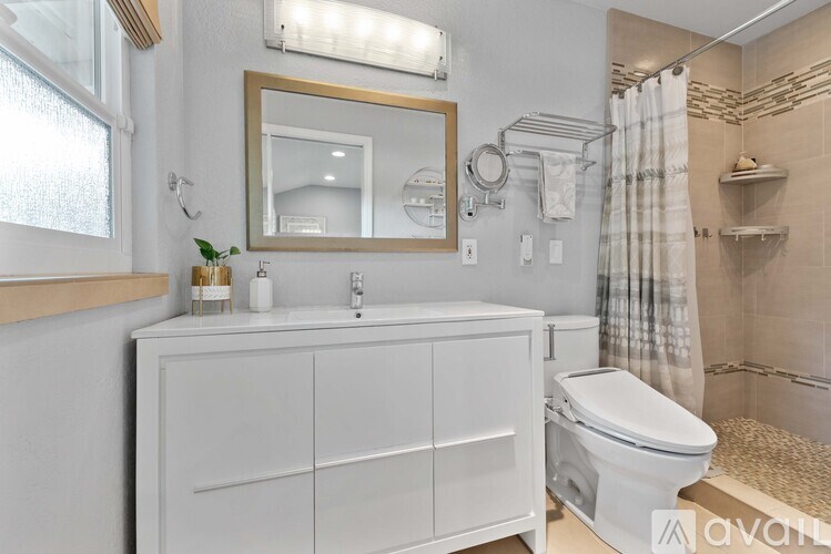 A white bathroom with a mirror, sink, and toilet.