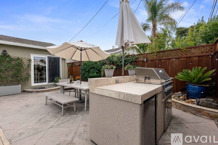 A patio with a table, chairs, and an umbrella.