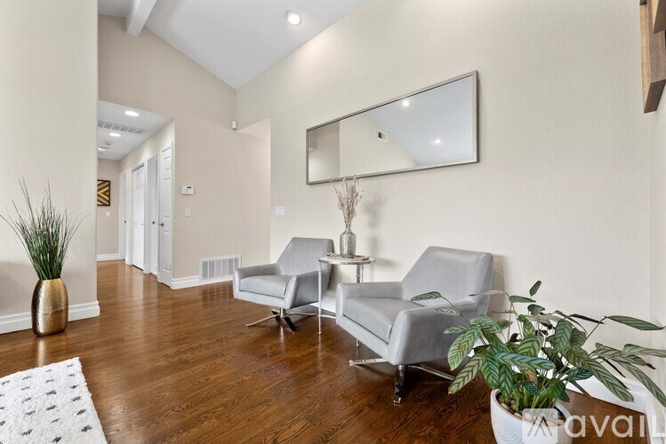 A living room with a grey sofa and a mirror on the wall.