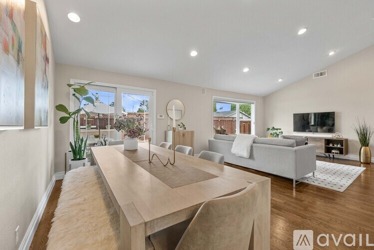 A modern living room with a wooden dining table and grey sofa.