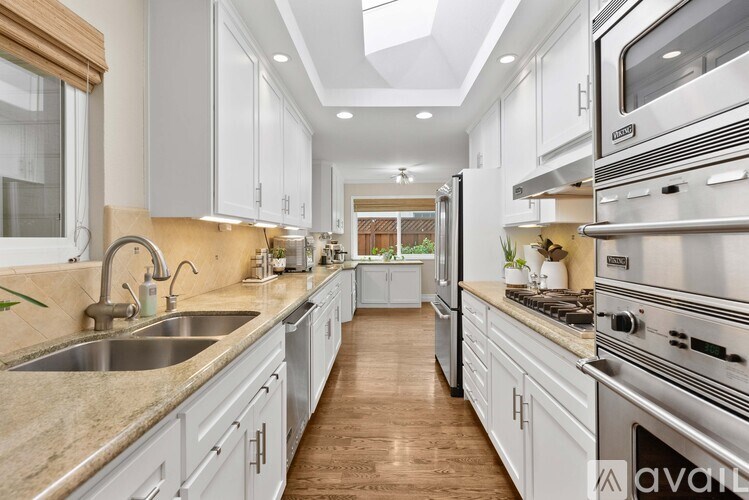 A modern kitchen with stainless steel appliances and wooden floors.