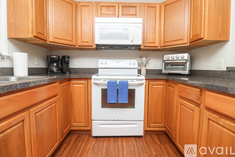 A kitchen with wooden cabinets and a white stove top oven.