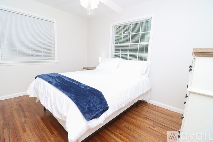 A bedroom with a white bed and a blue blanket.