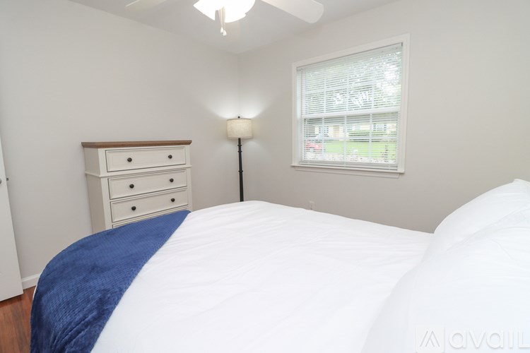 A bedroom with a bed, dresser, and window.