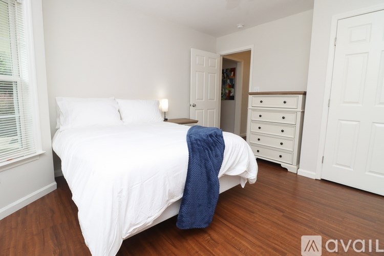 A bedroom with a white bed and a blue blanket.