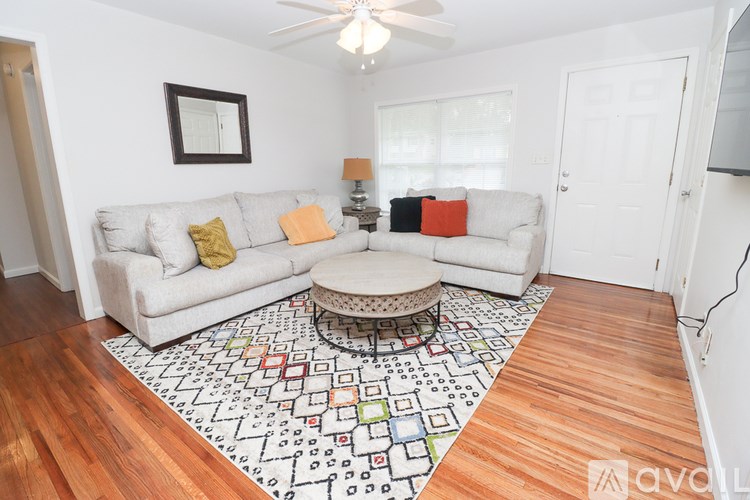 A living room with a white couch, a rug with a pattern, and a ceiling fan.