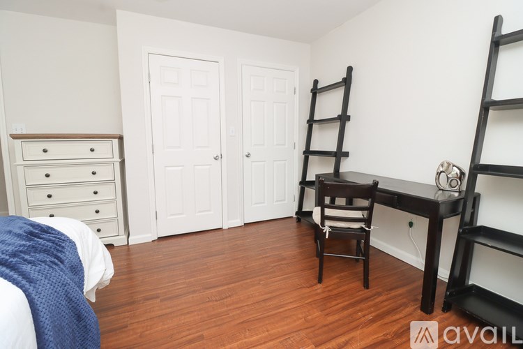 A room with a bed, a desk with a chair, and two doors.