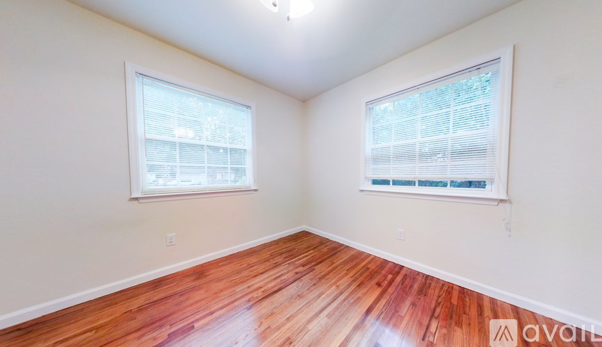 A room with wooden floors and two windows.