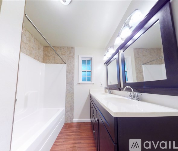 A bathroom with a white tub, sink, and mirror.