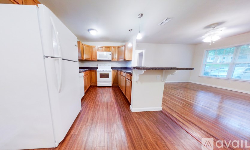A kitchen with white appliances and wooden floors.