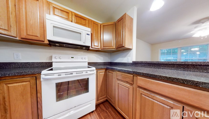 A kitchen with wooden cabinets and a white stove top oven.