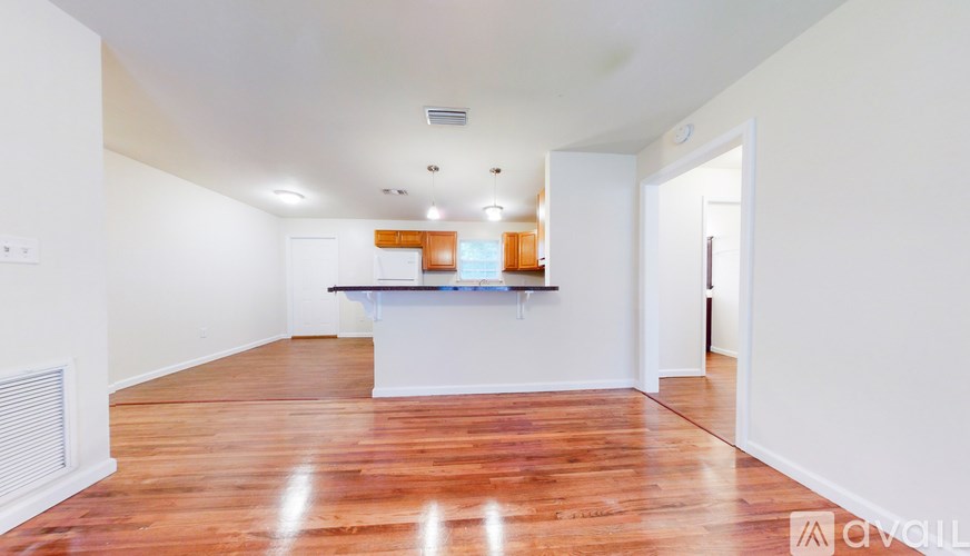 A spacious room with wooden floors and white walls.