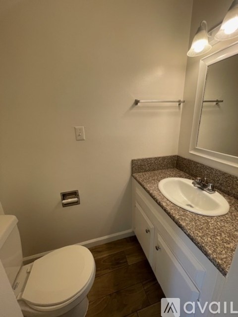 A bathroom with a toilet, sink, and mirror.
