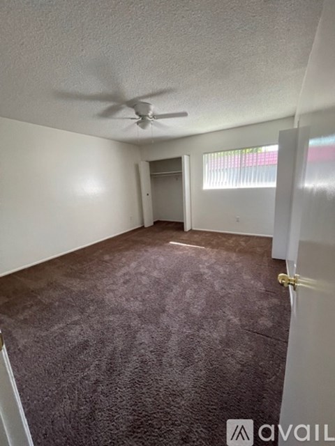 A room with a ceiling fan and carpeted floor.