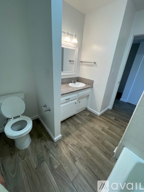 A bathroom with a toilet, sink, and mirror.