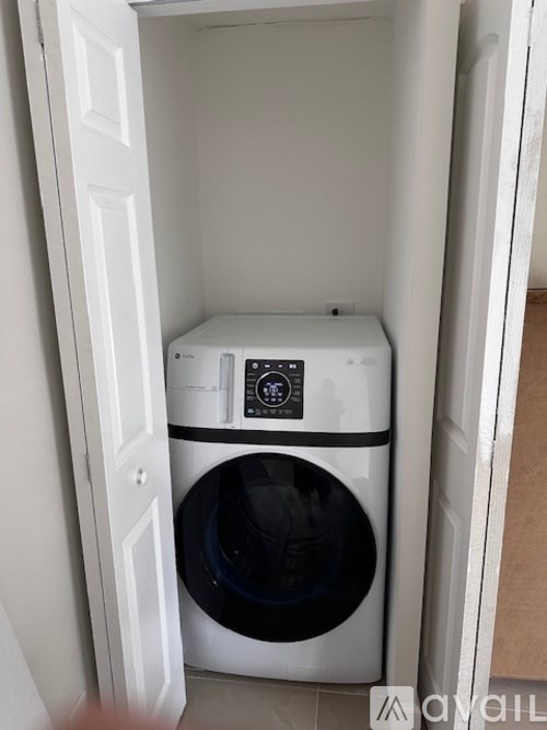 A white washing machine is in a white cabinet.