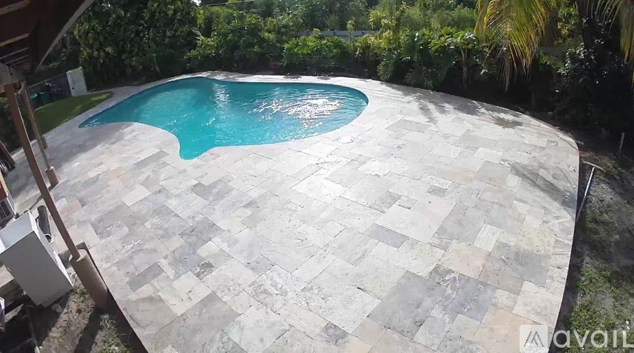 A pool surrounded by a stone patio.