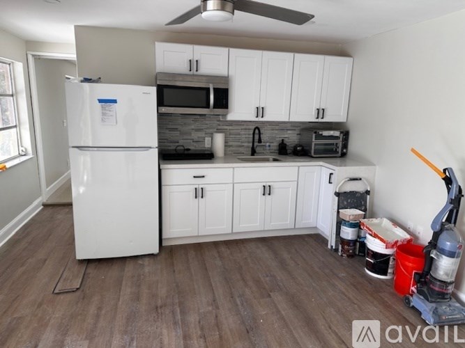 A kitchen with white cabinets and a white refrigerator.