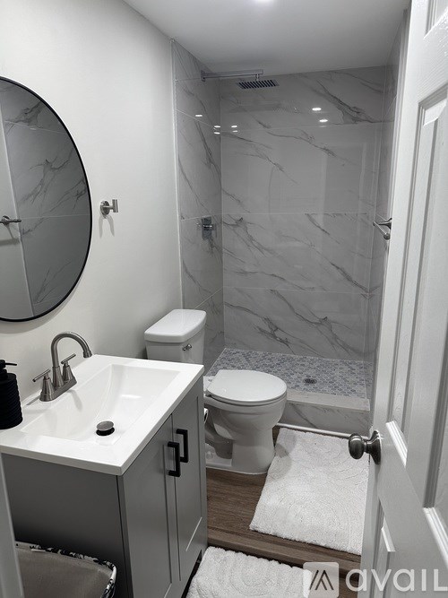 A bathroom with a marble tile shower and a white toilet.