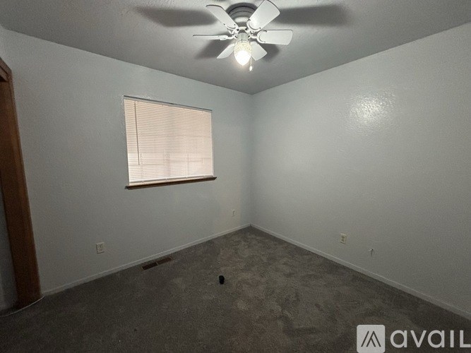 A room with a ceiling fan and a window with blinds.