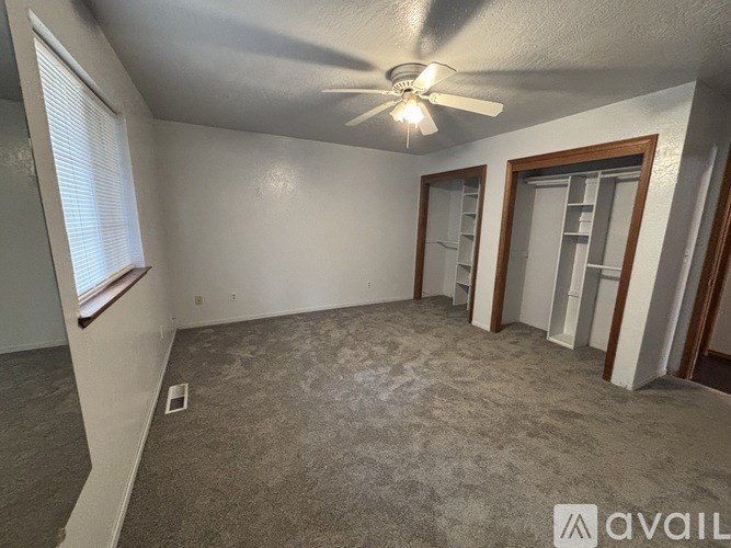 A room with a ceiling fan and carpeted floor.