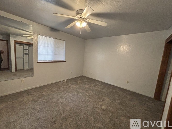 A room with a ceiling fan and carpeted floor.