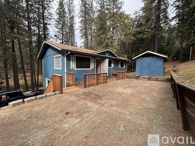 A blue house with a brown roof is surrounded by trees.