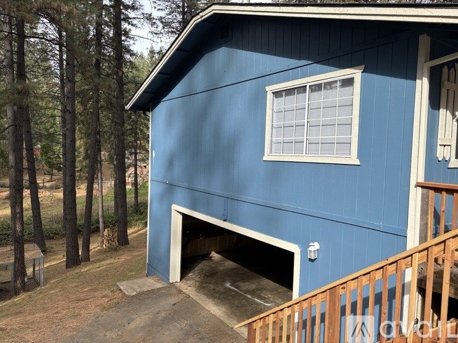 A blue house with a white window and a doorway leading to a garage.