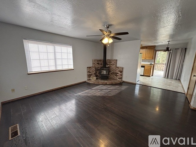 A room with a brick fireplace and a ceiling fan.