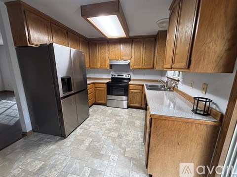 A kitchen with wooden cabinets and a black refrigerator.