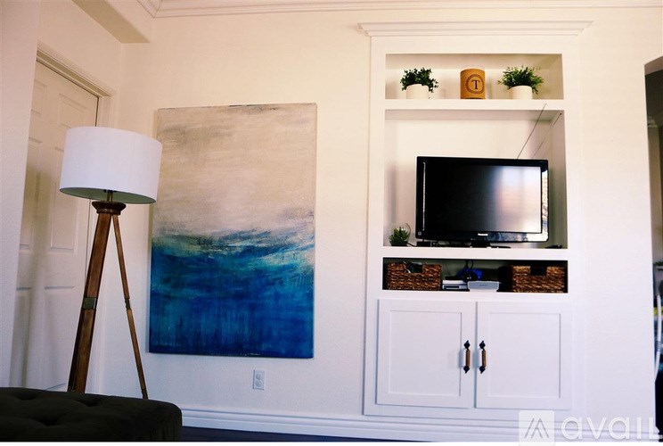 A living room with a painting, a lamp, and a television.