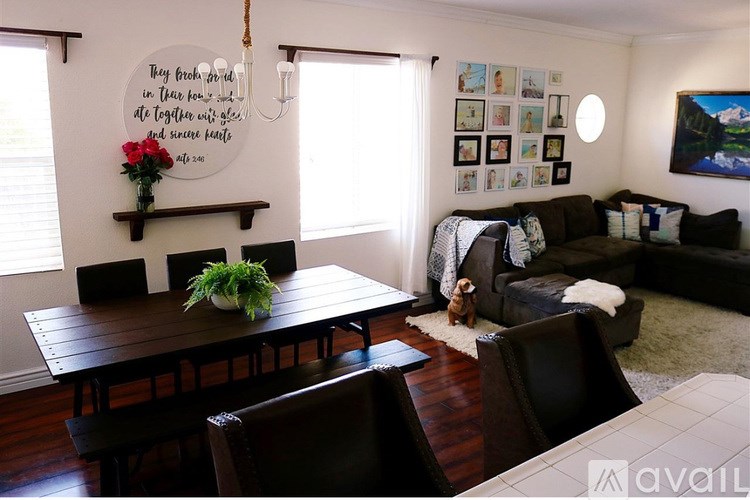 A living room with a wooden table and chairs, a couch, and pictures on the wall.