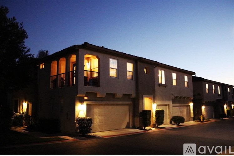 A row of townhouses are lit up at dusk.