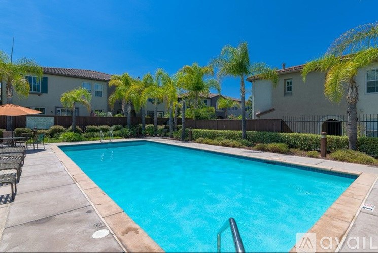 A pool surrounded by palm trees and a building in the background.