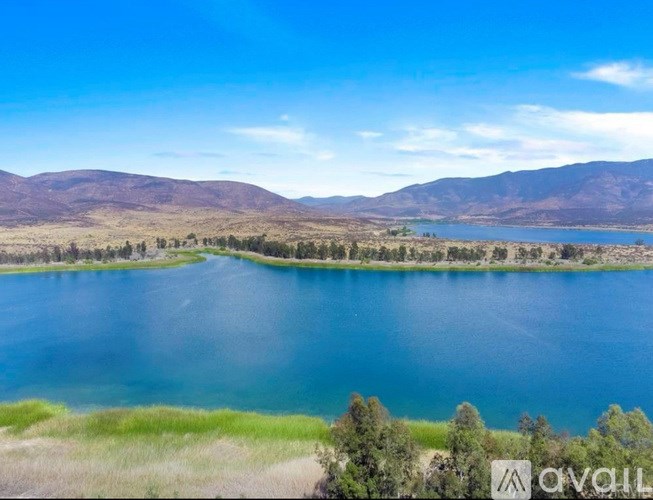 A large body of water surrounded by greenery and mountains.
