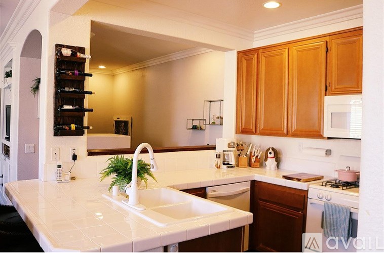 A kitchen with a white counter top and wooden cabinets.