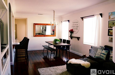 A living room with a black couch and a wooden floor.
