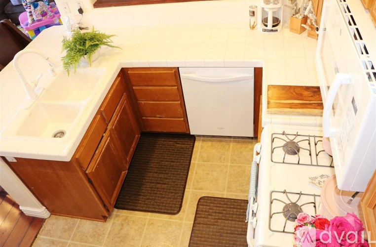A small kitchen with a white stove top oven and a white dishwasher.