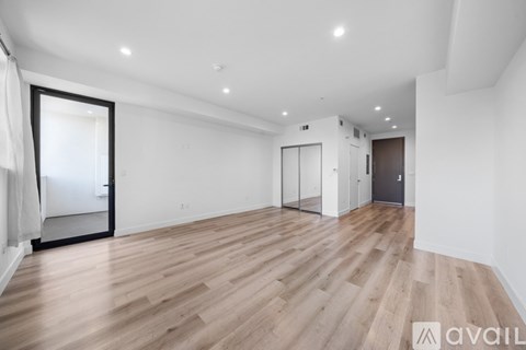 A spacious room with wooden flooring and white walls.