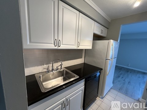 A kitchen with white cabinets and a black countertop.