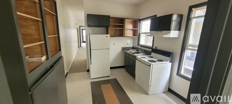 A kitchen with white appliances and a brown rug.