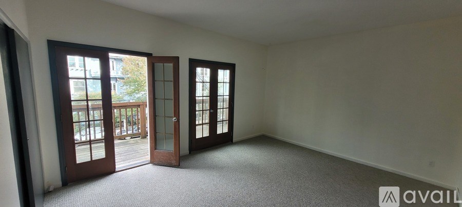 A room with a carpeted floor and a balcony with glass doors.
