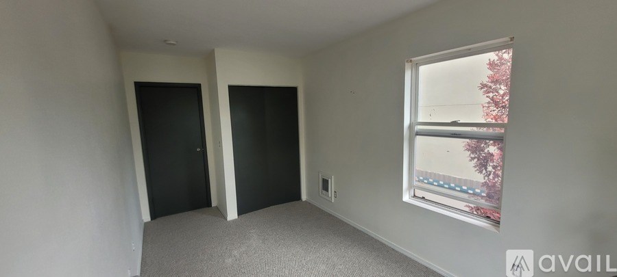 A room with two doors and a window with a view of trees outside.