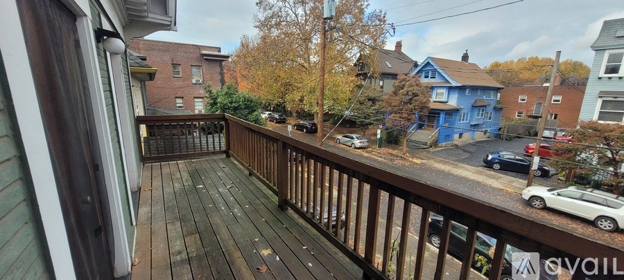 A balcony with a railing overlooks a street with cars and houses.
