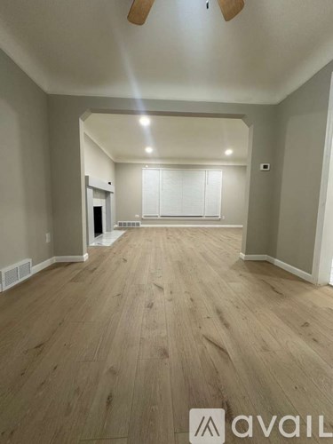 A spacious room with wooden flooring and white walls.