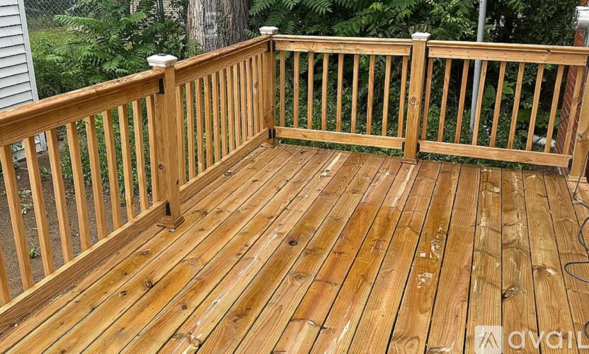 A wooden deck with a railing and a tree in the background.