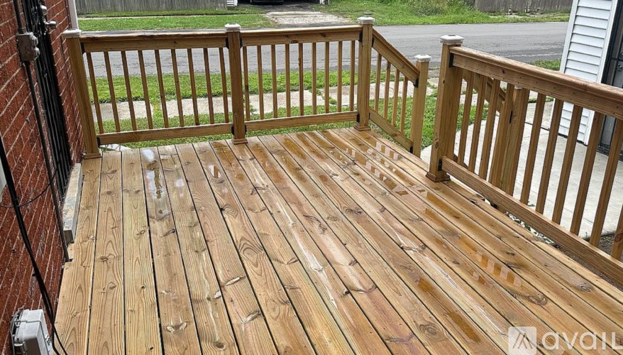 A wooden deck with a railing and a brick wall.