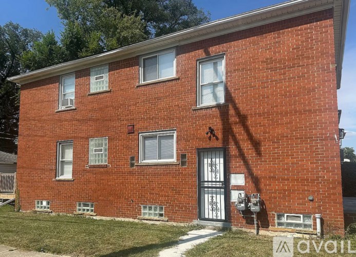 A red brick house with a black door and a mailbox on the right side.